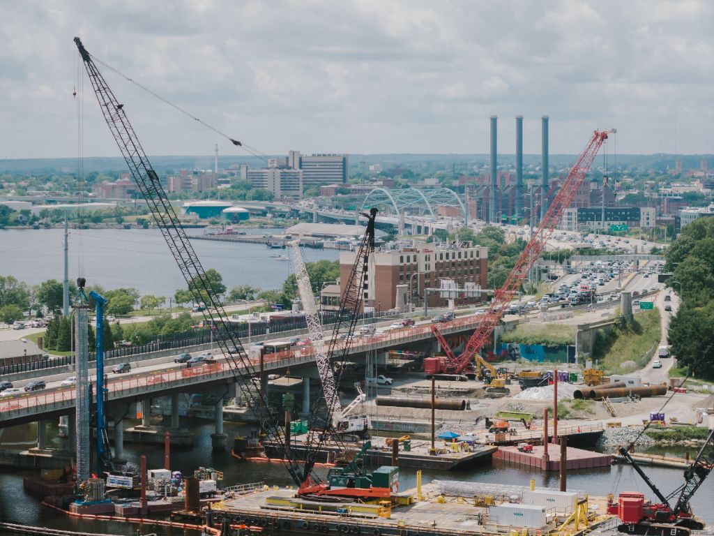 Aerial view of large-scale bridge construction with multiple cranes over waterway